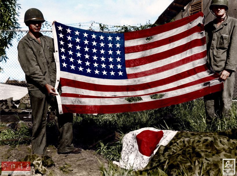 攻占日军阵地后,美军士兵向记者展示美国国旗.